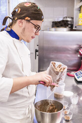 Männlicher Bäcker bei der Herstellung eines Spritzbeutels mit Schokoladencreme am Küchentisch im Labor - CAVF62765