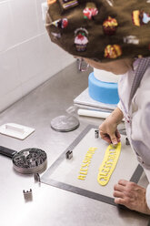Seitenansicht einer Bäckerin beim Schneiden von Teig mit einer Ausstechform auf einem Küchentisch im Labor - CAVF62773