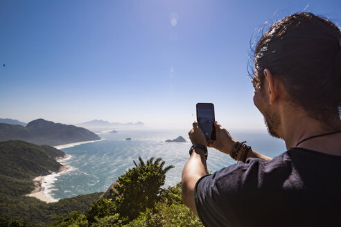 Tourist fotografiert das Meer mit Smartphone gegen den Himmel an einem sonnigen Tag - CAVF62780