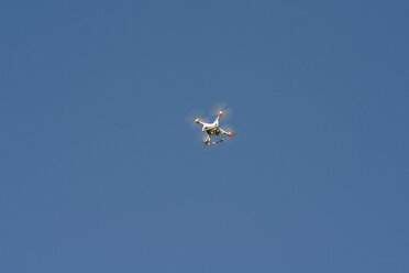 Low angle view of quadcopter flying against clear blue sky during sunny day - CAVF62792