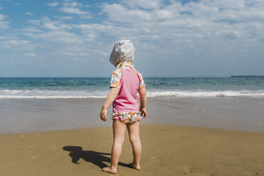 Rückansicht eines Mädchens, das am Strand im Sand steht, gegen einen bewölkten Himmel an einem sonnigen Tag - CAVF62834