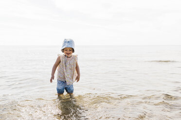 Cute happy girl wearing hat while standing in sea against sky - CAVF62835