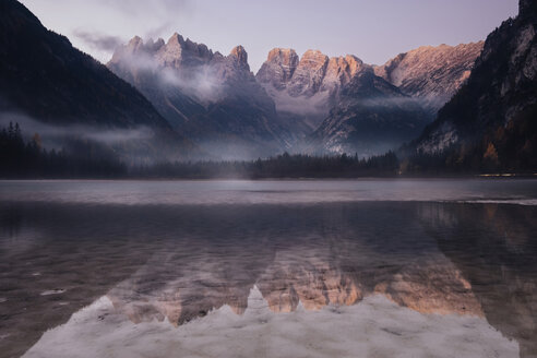 Scenic view of mountains reflecting on calm lake against sky during sunrise - CAVF62880