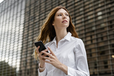 Young businesswoman in the city, using smartphone - GIOF05819