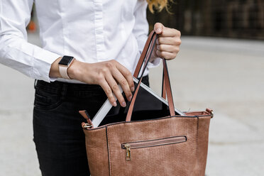 Businesswoman taking digital tablet out of her bag - GIOF05823