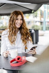 Young businesswoman sitting in cafe, using smartphone - GIOF05831