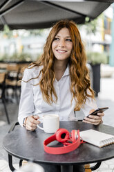 Young businesswoman sitting in cafe, using smartphone - GIOF05832