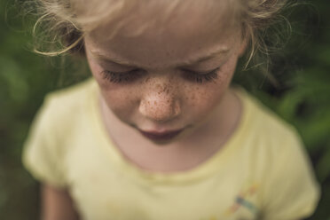 Nahaufnahme eines Mädchens mit Sommersprossen, das im Wald steht - CAVF62898