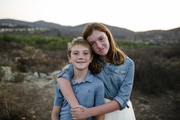 Portrait of loving siblings standing on field during sunset - CAVF62972