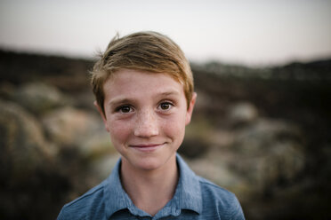 Nahaufnahme eines lächelnden Jungen auf einem Feld bei Sonnenuntergang - CAVF62980
