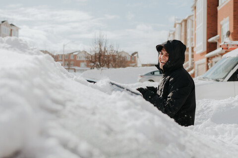 Mann lachend neben schneebedecktem Fahrzeug, Toronto, Kanada, lizenzfreies Stockfoto