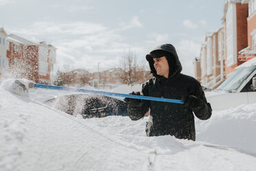 Mann räumt schneebedecktes Fahrzeug mit Besen, Toronto, Kanada - ISF20961