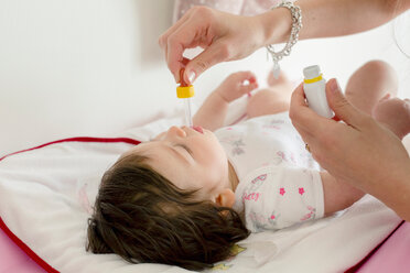 Mutter füttert Baby Mädchen Medizin im Bett - ISF20976