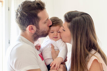 Parents kissing baby girl's cheeks at home - ISF20983