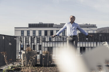 Mature businessman having a break on roof terrace - UUF16690