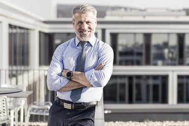 Porträt eines lächelnden, selbstbewussten reifen Geschäftsmannes auf einer Dachterrasse - UUF16718