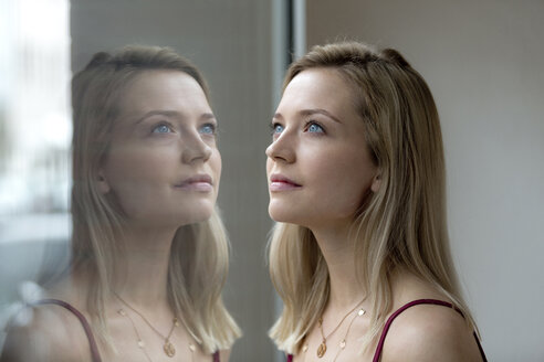 Porträt einer blonden jungen Frau und ihr Spiegelbild auf einer Fensterscheibe - FLLF00063