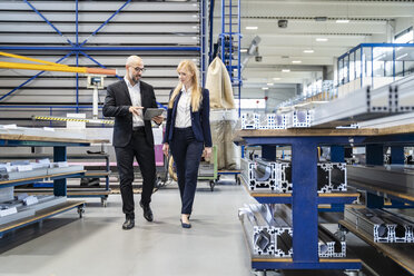 Businessman and businesswoman with tablet walking in factory - DIGF06050