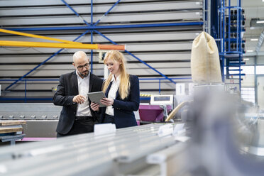 Businessman and businesswoman with tablet discussing in factory - DIGF06052
