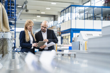 Geschäftsmann und Geschäftsfrau mit Tablet diskutieren in einer Fabrik - DIGF06053