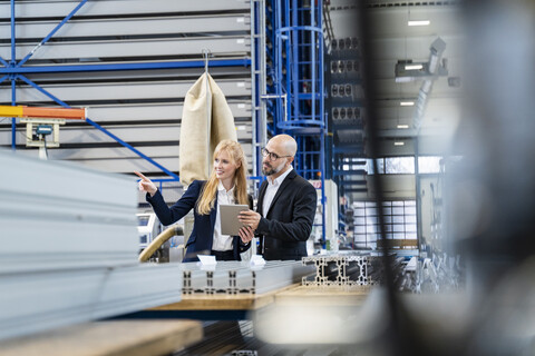 Geschäftsmann und Geschäftsfrau mit Tablet diskutieren in einer Fabrik, lizenzfreies Stockfoto