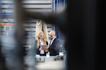 Geschäftsmann und Geschäftsfrau mit Tablet diskutieren in einer Fabrik - DIGF06055