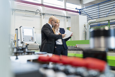 Businessman and businesswoman looking at plan in factory - DIGF06078