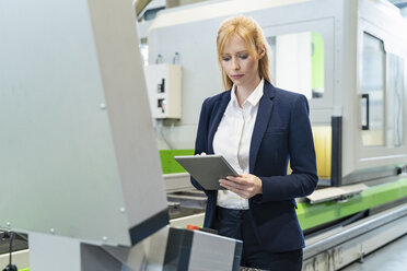 Geschäftsfrau benutzt Tablet an einer Maschine in einer Fabrik - DIGF06079