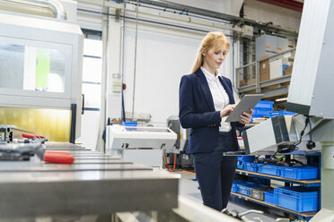 Businesswoman using tablet at machine in factory - DIGF06081