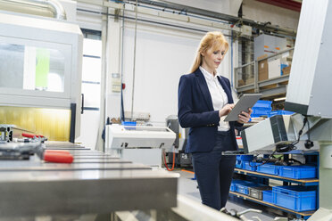 Geschäftsfrau benutzt Tablet an einer Maschine in einer Fabrik - DIGF06081