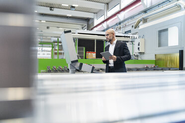 Businessman using tablet at machine in factory - DIGF06082