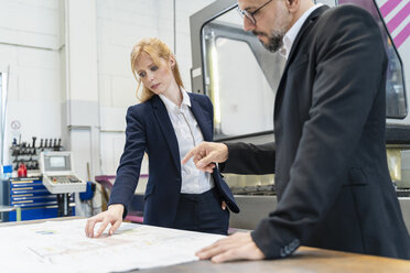 Businessman and businesswoman looking at plan on table in factory - DIGF06092