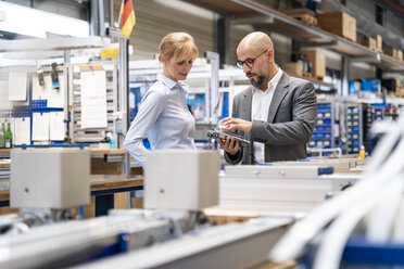 Businessman and businesswoman examining workpiece in factory - DIGF06119