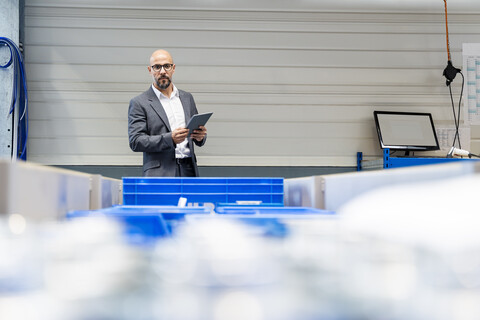 Geschäftsmann mit Tablet, der den Bestand in einer Fabrik überprüft, lizenzfreies Stockfoto