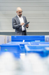 Businessman with tablet checking stock in factory - DIGF06128