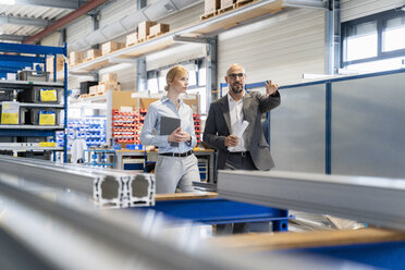 Businessman talking to businesswoman in factory - DIGF06137