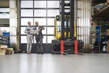 Businessman and businesswoman discussing plan in factory - DIGF06139