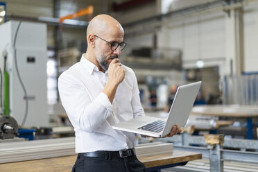 Focused businessman using laptop in factory - DIGF06151