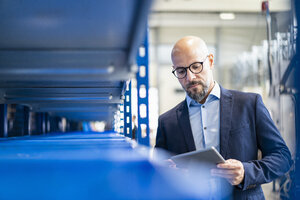 Businessman with tablet in factory storehouse - DIGF06167