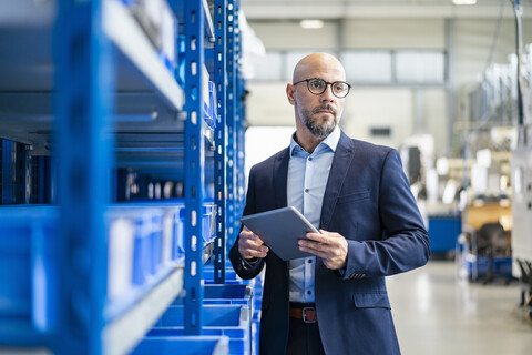 Geschäftsmann mit Tablet im Lager der Fabrik, lizenzfreies Stockfoto