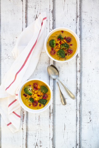 Currygericht mit Kürbis, Süßkartoffel, Brokkoli, Tomate, Granatapfelkernen und schwarzem Sesam in Schale, lizenzfreies Stockfoto