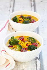 Curry dish with pumpkin, sweet potato, brokkoli, tomato, pomegranate seeds and black sesame in bowl - LVF07853