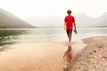 Junger Mann paddelt knöcheltief im See von Annecy, Annecy, Rhone-Alpes, Frankreich - CUF49531