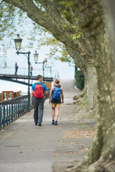 Mature man and young woman strolling along riverside, rear view, Annecy, Rhone-Alpes, France - CUF49535