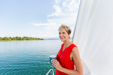 Mature woman having coffee while sailing on Chiemsee lake, Bavaria, Germany - CUF49612