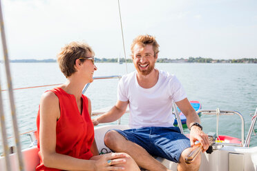 Young man and mature woman laughing on sailboat on Chiemsee lake, Bavaria, Germany - CUF49634