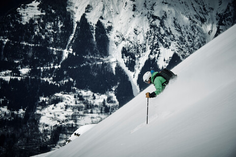 Männlicher Skifahrer, der einen steilen Berghang hinunterfährt, Alpe-d'Huez, Rhone-Alpes, Frankreich, lizenzfreies Stockfoto