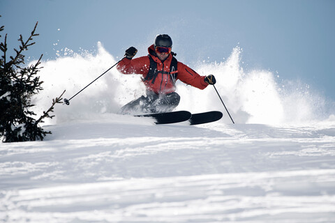 Männlicher Skifahrer, der beim Skifahren den Berg hinunterfährt, Alpe-d'Huez, Rhone-Alpes, Frankreich, lizenzfreies Stockfoto