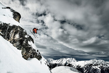 Male skier jumping mid air from rugged mountainside, Alpe-d'Huez, Rhone-Alpes, France - CUF49702