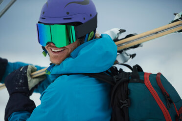 Männlicher Skifahrer mit Skiern, Blick über die Schulter, Porträt, Alpe-d'Huez, Rhone-Alpes, Frankreich - CUF49705